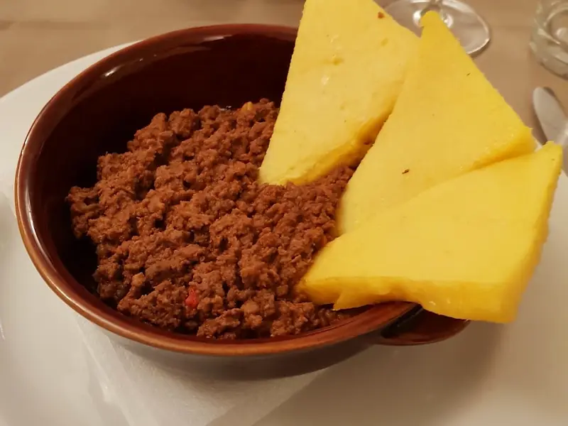 Picula di cavallo in un coccio, con fette di polenta